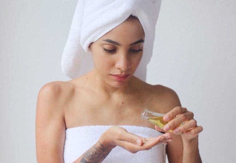 The girl uses oil to rejuvenate her skin